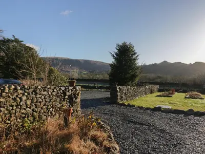 a stone fence in front of a field with a tree at The Barn in Seascale
