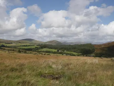 a field of grass with mountains in the background at The Barn in Seascale