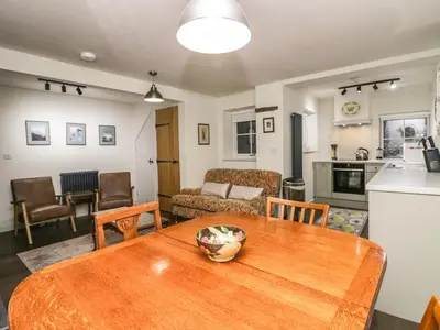a kitchen and living room with a wooden table at Church How Cottage in Seascale