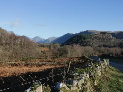 a fence on the side of a hill with a road at Church How Cottage in Seascale