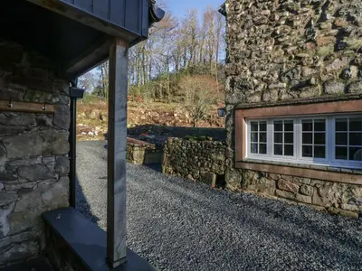 an open door to a stone building with a window at Church How Cottage in Seascale