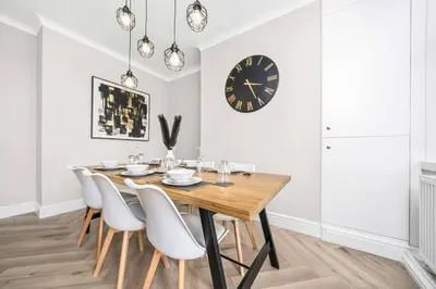 a dining room table with white chairs and a clock at Central Gretna Luxury 4 bed in Gretna