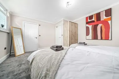 a white bedroom with two beds and a mirror at Central Gretna Luxury 4 bed in Gretna