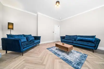 a living room with two blue couches and a coffee table at Central Gretna Luxury 4 bed in Gretna