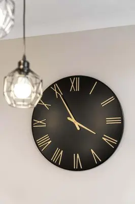a black clock hanging from a ceiling with a light at Central Gretna Luxury 4 bed in Gretna
