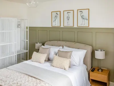 a bedroom with a white bed with four pictures on the wall at Flag Cottage in Carsethorn