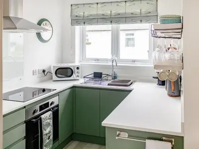 a kitchen with green cabinets and a microwave at Flag Cottage in Carsethorn