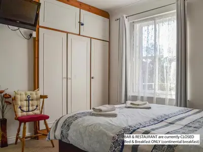 a bedroom with a bed and a chair and a window at Hope & Anchor, Hadrian's Wall, Port Carlisle, Solway Firth, Area of Natural Beauty in Port Carlisle