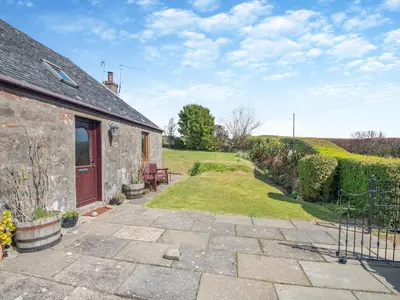 a stone house with a patio and a yard at Kilbride Cottage-Uk46886 in Kilmory