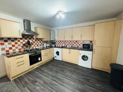 a kitchen with wooden cabinets and a washer and dryer at Curwen Apartment - 2 Bedrooms - Sleeps 6 in Workington