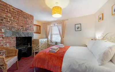 a bedroom with a bed and a brick wall at Beagle Cottage in Keswick
