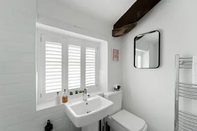 a bathroom with a sink and a toilet and a mirror at Darwin Cottage in Keswick