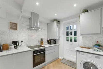 a white kitchen with a sink and a dishwasher at Darwin Cottage in Keswick