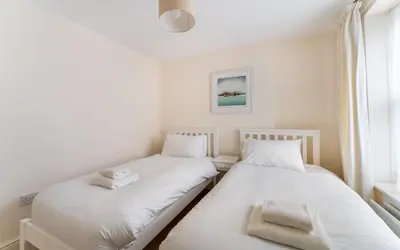 two beds in a room with white sheets and towels at Ratstone Cottage in Keswick