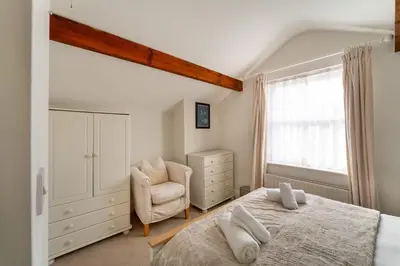 a bedroom with a bed and a chair and a window at Ratstone Cottage in Keswick