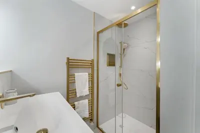a bathroom with a shower with a glass door at Ratstone Cottage in Keswick