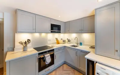 a kitchen with white cabinets and white counters at Ratstone Cottage in Keswick