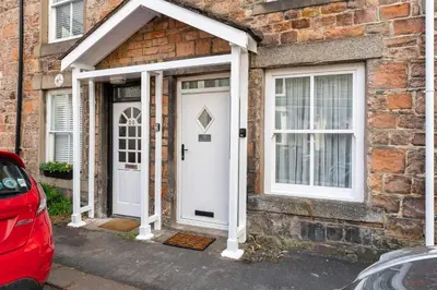 a brick house with a white door and windows at Ratstone Cottage in Keswick