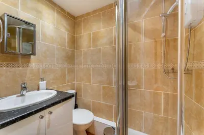 a bathroom with a shower and a toilet and a sink at Sunny Cottage in Keswick