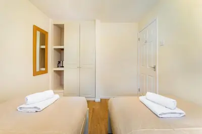 two beds in a room with white walls at Sunny Cottage in Keswick