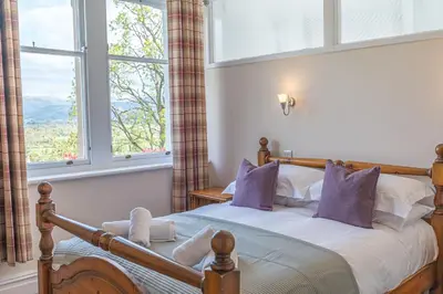 a bedroom with a bed with purple pillows and a window at Thwaite Howe in Keswick