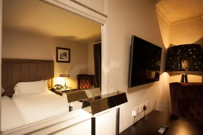 a hotel room with a bed and a mirror at Strathaven Hotel in Strathaven