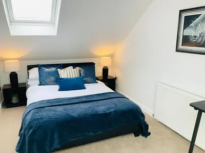 a bedroom with a large bed with blue pillows at Harling House - Prestwick - 4 bedrooms in Prestwick