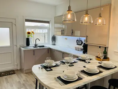 a kitchen with a table with plates and wine glasses at Harling House - Prestwick - 4 bedrooms in Prestwick