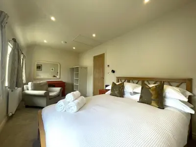 a bedroom with a large white bed and a chair at Glenn Cottage in Braithwaite