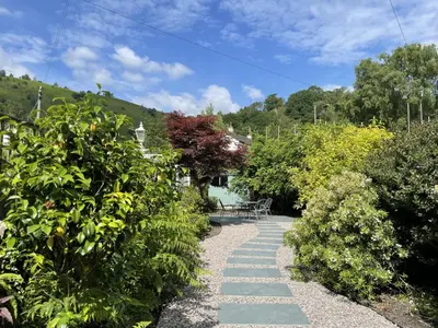 a garden path with a table and bushes at Glenn Cottage in Braithwaite