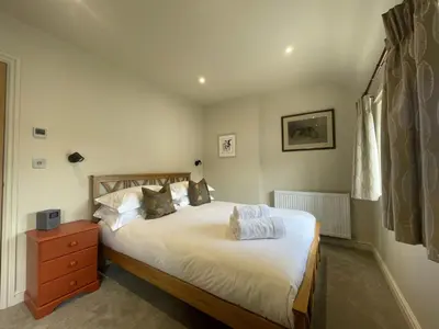 a bedroom with a bed and a dresser and a window at Glenn Cottage in Braithwaite