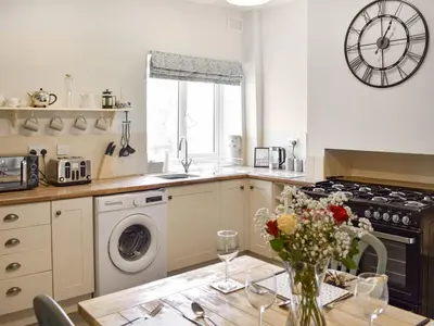 a kitchen with a table with a vase of flowers on it at Reed Cottage in Aspatria