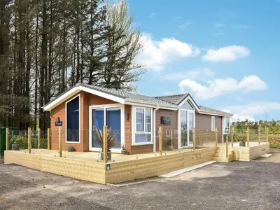 a small house with a large wooden deck at Solway Escape in Plumbland