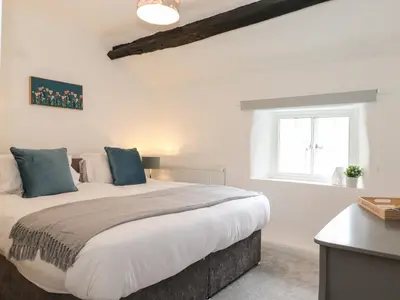 a bedroom with a large bed with blue pillows at One Side House Farm in Ambleside