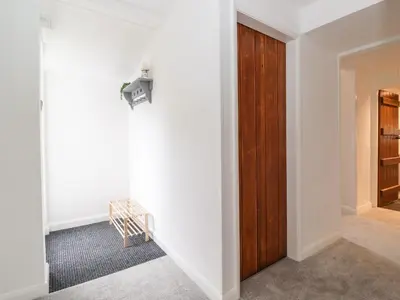 a hallway with white walls and a wooden door at One Side House Farm in Ambleside