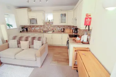 a living room with a couch and a kitchen at Bramble Cottage perfect for a relaxing romantic break in Keswick in Keswick