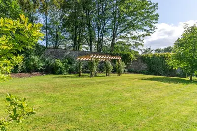 a garden with a pergola in the grass at The Gardeners Cottage, Hutton John is a luxurious cottage with hot tub 10 minutes from Lake Ullswater in Penruddock