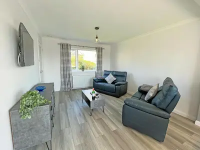 a living room with two couches and a tv at Driftwood Cottage in Portpatrick