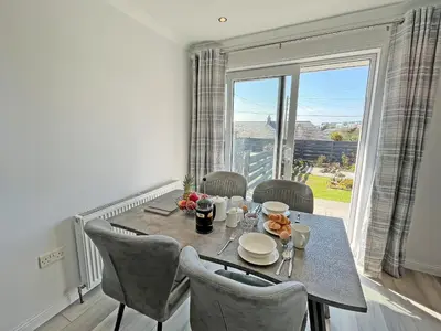 a dining room with a table and chairs and a large window at Driftwood Cottage in Portpatrick