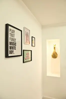 a white wall with framed pictures and a picture of a cat at Quirky & Comfortable Residence in Workington
