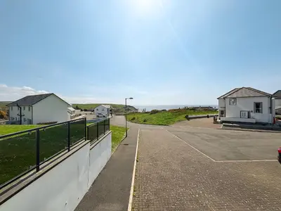 a view of a road with a fence and houses at Sandpipers in Portpatrick
