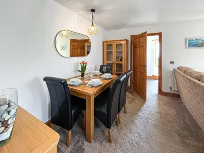 a dining room with a wooden table and black chairs at Sandpipers in Portpatrick