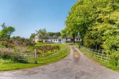 a dirt road with a fence next to a house at Courtyard Cottages, Barn Cottage in Wigtown