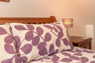 a bed with a pillow and a table with a lamp at Courtyard Cottages, Barn Cottage in Wigtown