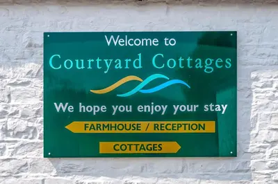 a sign on a wall that says welcome to couryardcolectales at Courtyard Cottages, Garden Cottage in Wigtown