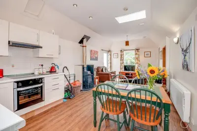 a kitchen with a table and chairs in a room at Courtyard Cottages, Garden Cottage in Wigtown