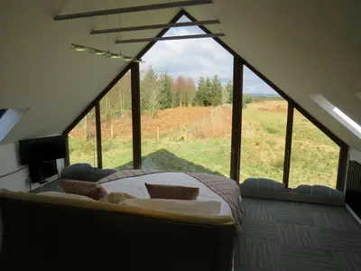 a bedroom with a bed in front of a large window at Cot Cottage - Panoramic Views & Hot Tub! in Castle Douglas