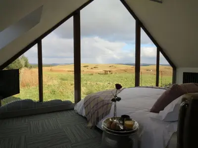 a bedroom with a bed with a view of a field at Cot Cottage - Panoramic Views & Hot Tub! in Castle Douglas