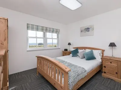 a bedroom with a large bed and a window at Cot Cottage - Panoramic Views & Hot Tub! in Castle Douglas