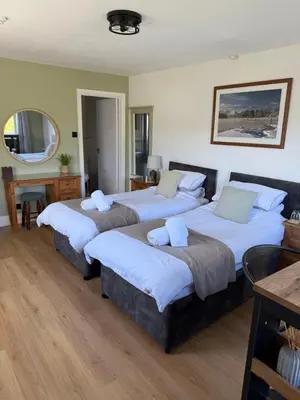a bedroom with three beds and a mirror at Shemara rooms in Keswick